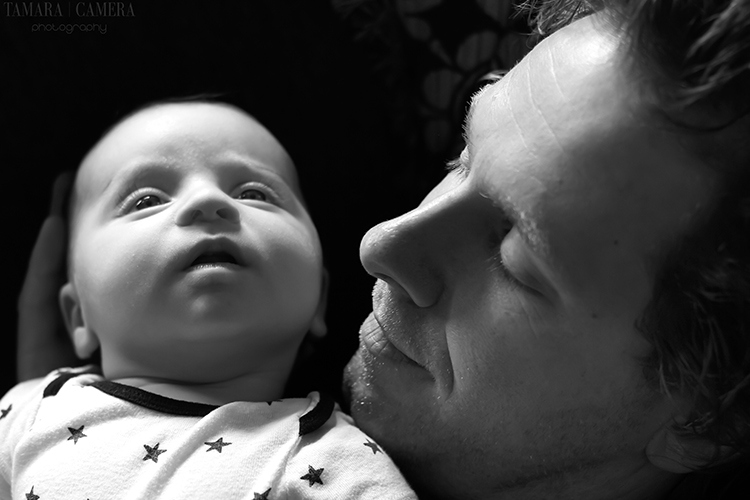 High tonal contrast photos are primarily light and dark or white and black elements with a sharp difference between them like this dramatic image | Photography Tips | Father and baby in black and white.