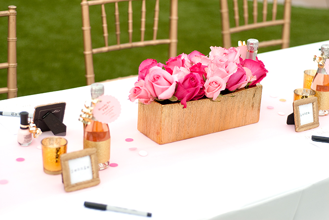 Pink roses for the centerpiece, and small frames and champagne bottles for place settings. 