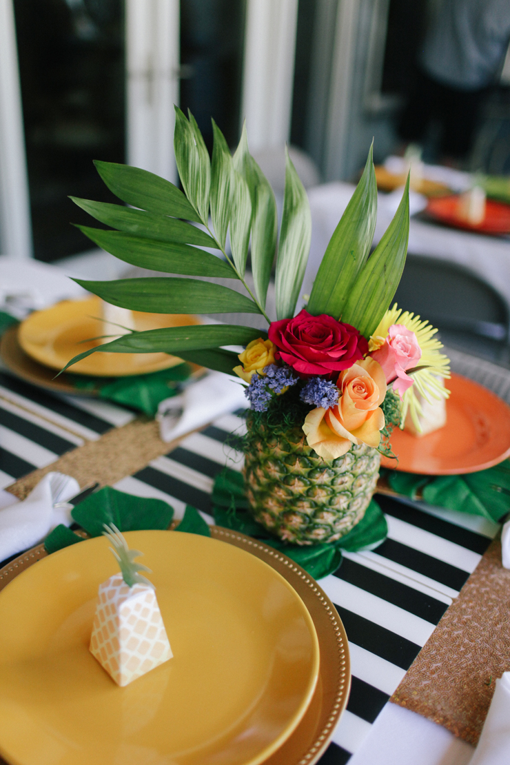 Combine bright colors and black and white place mats! The pineapple flower arrangements are the perfect final touch for tropical party decor.
