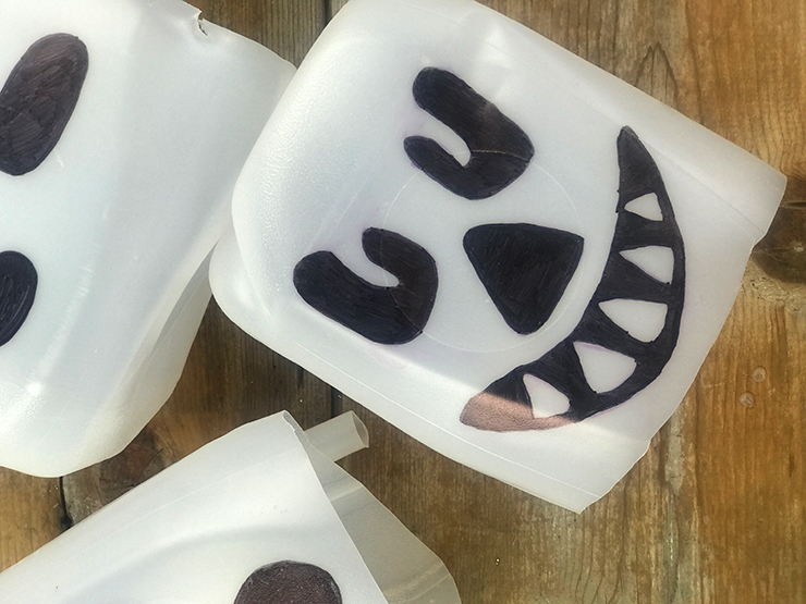 Draw spooky faces on milk jugs for a great Halloween DIY!