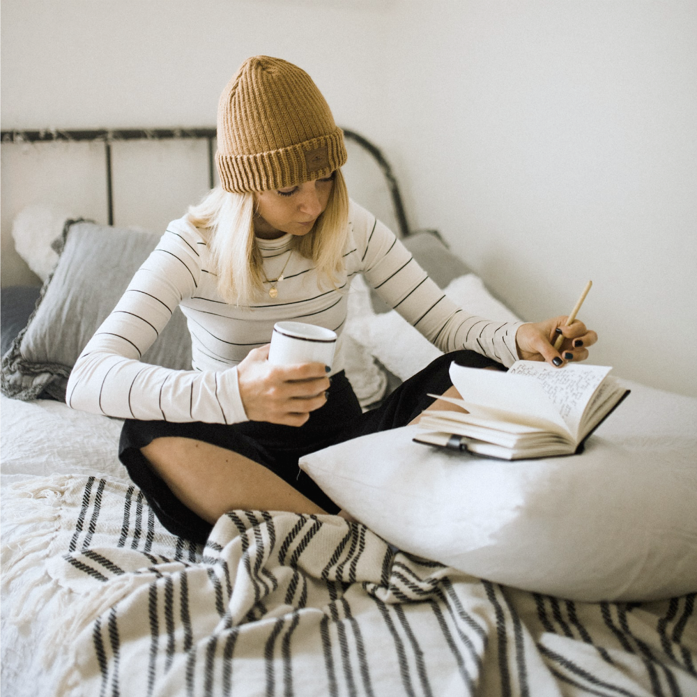 woman in bed reading and writing