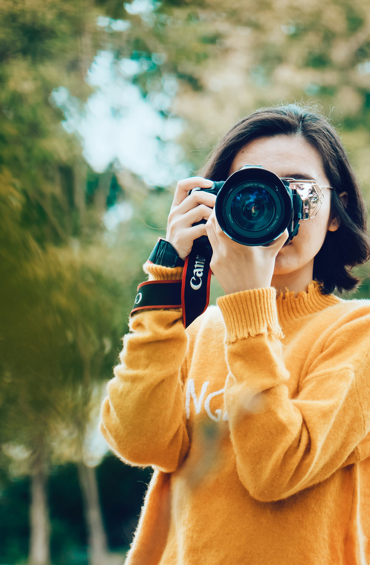 Woman holding DSLR camera taking a photograph