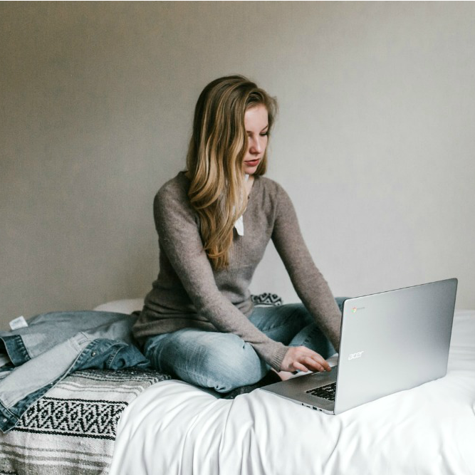 woman sitting on bed with computer