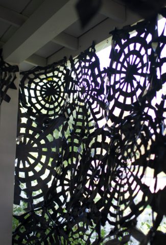 Spiderwebs made with black trash bags hanging on a porch.