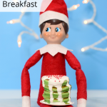 Elf on the Shelf mini pancake breakfast | Elf holding stack of green pancakes topped with icing and sprinkles
