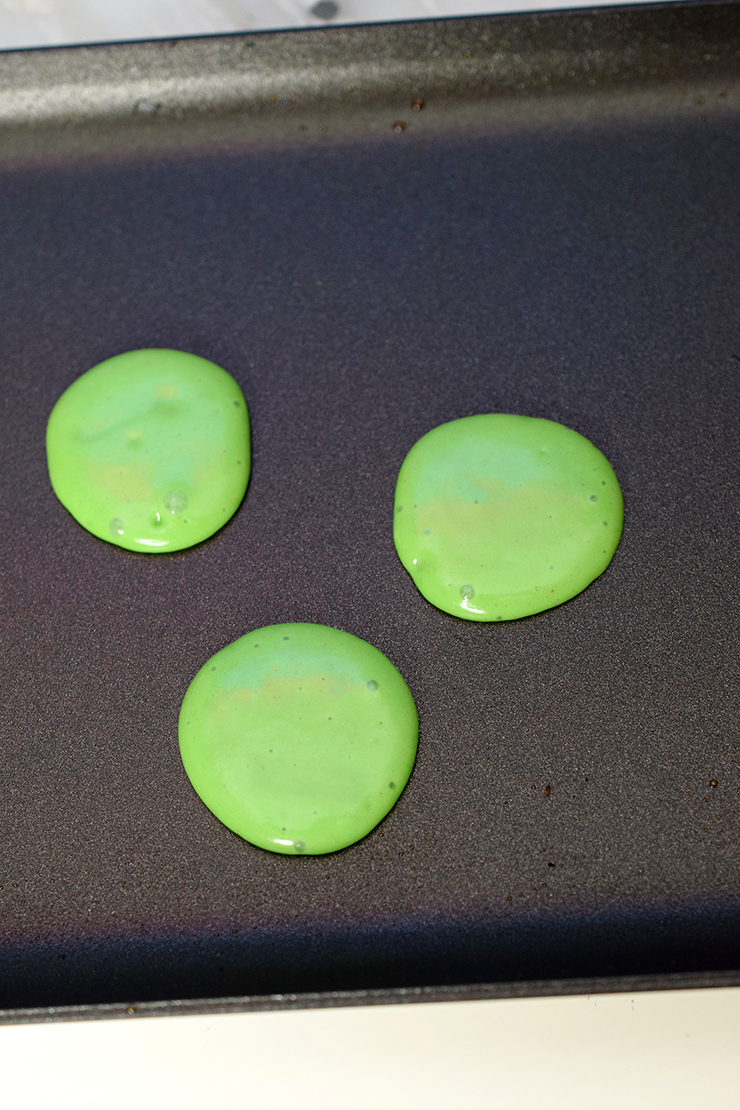 green mini pancakes on the griddle