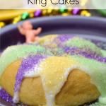 Mini crescent roll king cakes on purple plate with mardi gras beads and plastic baby in the background.
