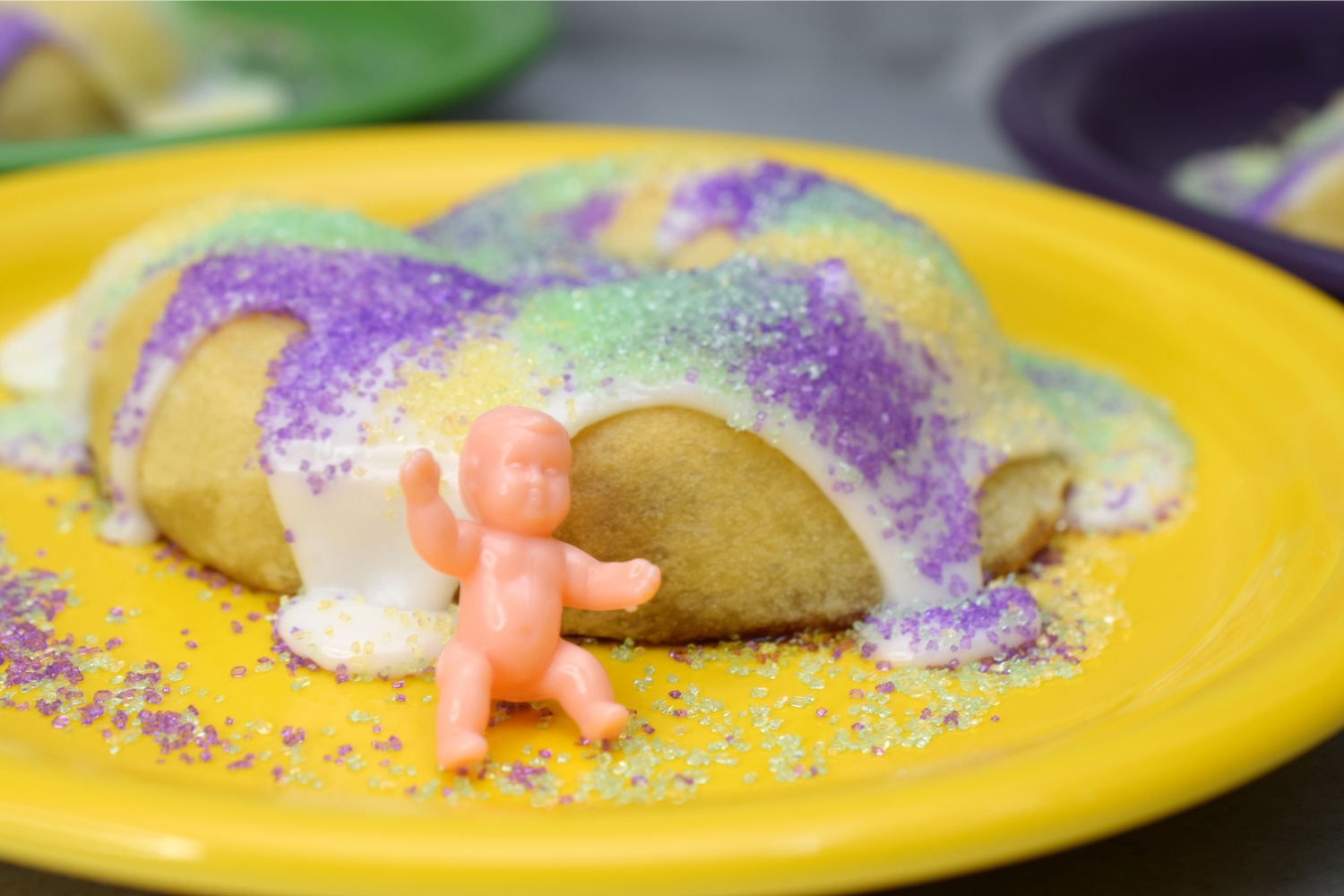 King Cake on a yellow plate with a plastic baby.