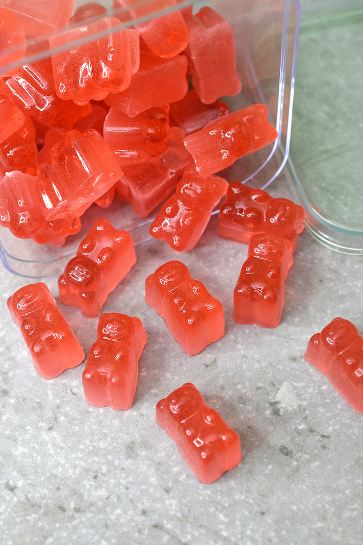 Rosé gummy bears spilling out of container.