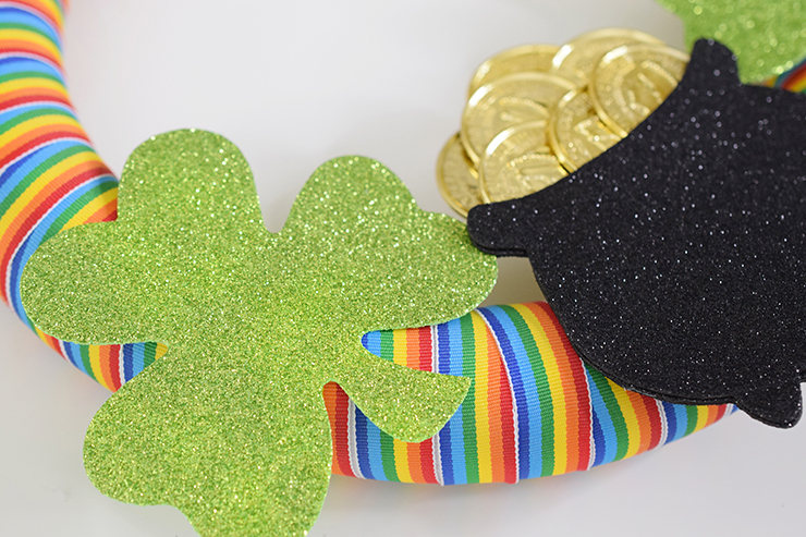 Shamrocks and pot of gold hot glued on rainbow wreath.
