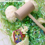 Chocolate Piñata Easter Eggs with wooden mallet on green Easter grass.