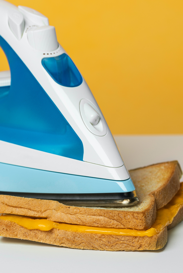 An iron pressing down on a grilled cheese sandwich.