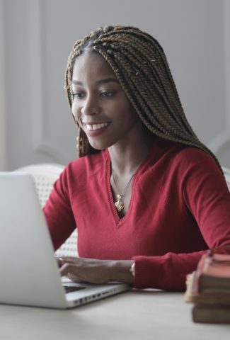 Woman sitting in a mostly white room typing on a computer.