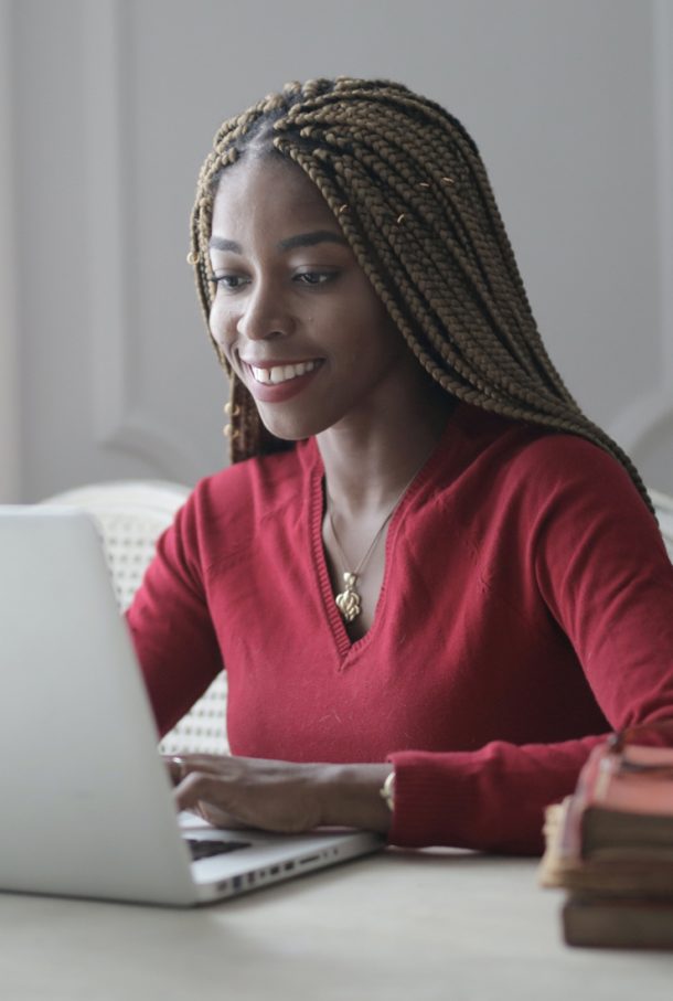 Woman sitting in a mostly white room typing on a computer.