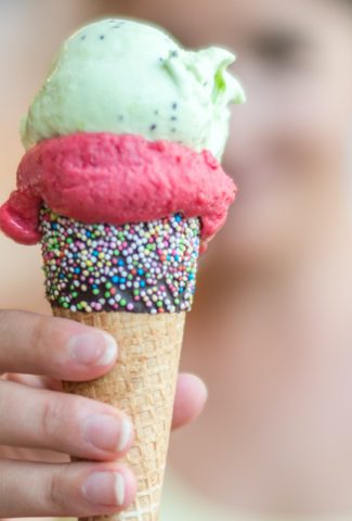 National Ice Cream Day - hand holding an ice cream cone with three different scoops of ice cream.