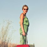 Woman with a red suitcase standing in the road under the words 12 must-have packing supplies for your next trip.