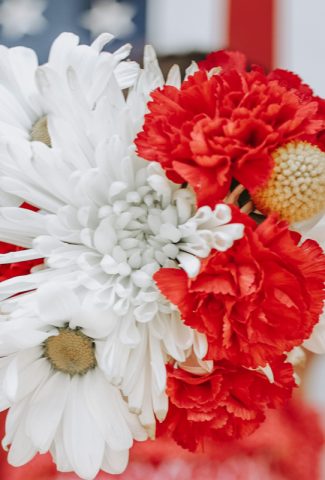 Red and white flowers in front of an American flag.