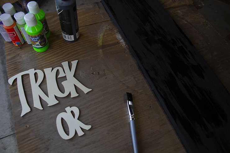 Bottles or paint, paint brush, and letters to spell trick or treat. 