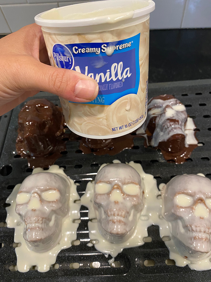 Cakes sitting on cooking rack with frosting poured over them. A hand holding Pillsbury Vanilla frosting.