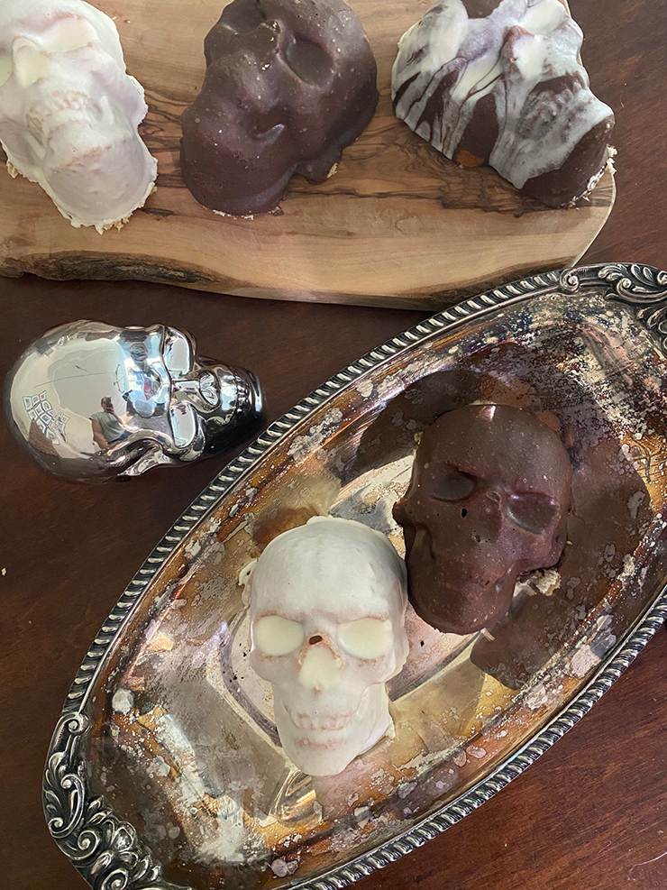 Mini cakes shaped like skulls with brown and white frosting.