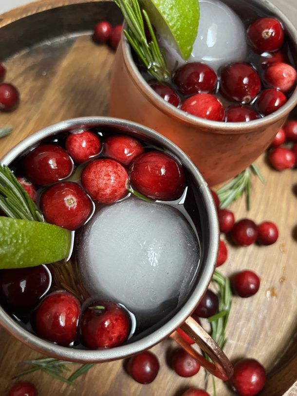 Drink with cranberries and a large, round ice cube.