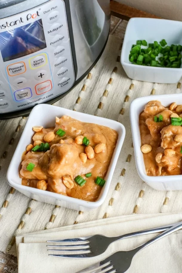 Peanut butter chicken in square bowls sitting in front of an Instant Pot.