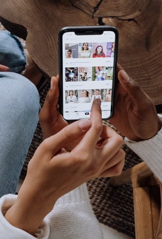 Woman holding a phone looking at TikTok.