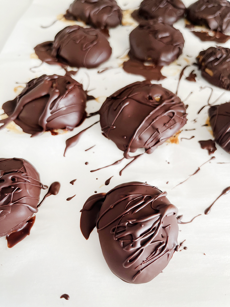 Peanut butter covered in chocolate on parchment paper.