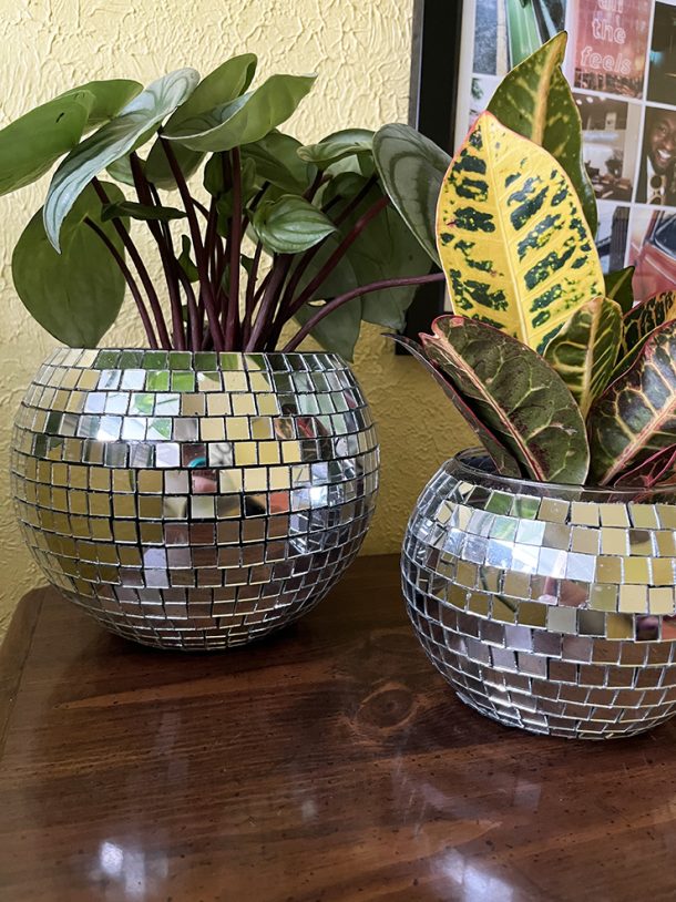 Two planters that look like disco balls sitting on a wooden table.