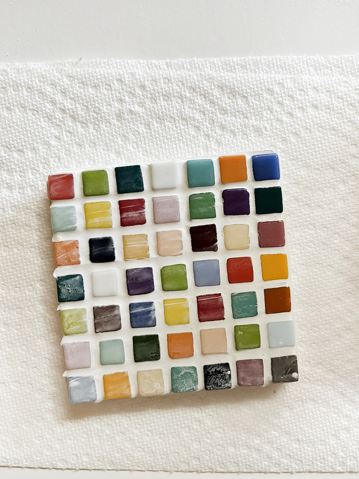 Coaster with tiles streaked with grout that needs to be wiped off.