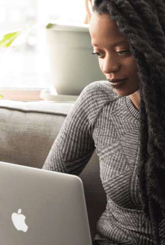 Woman sitting on a couch working on her computer.