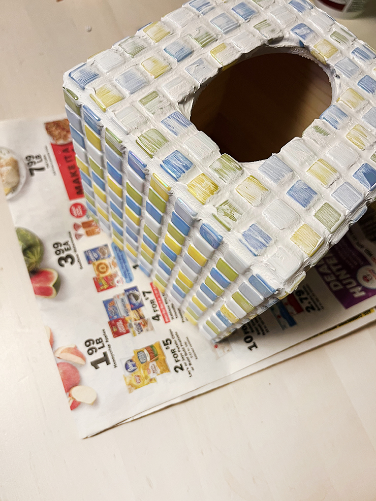 Top view of the tissue box with tiles spread out on it and grout covering the tiles.