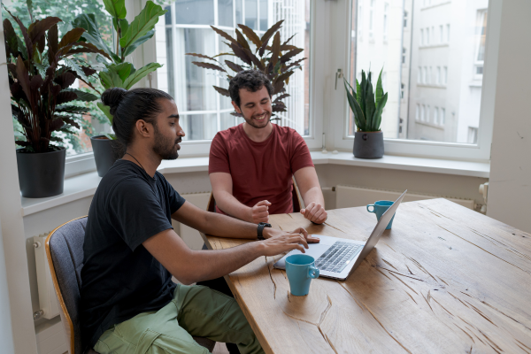 Two men sitting at a table working on a computer.