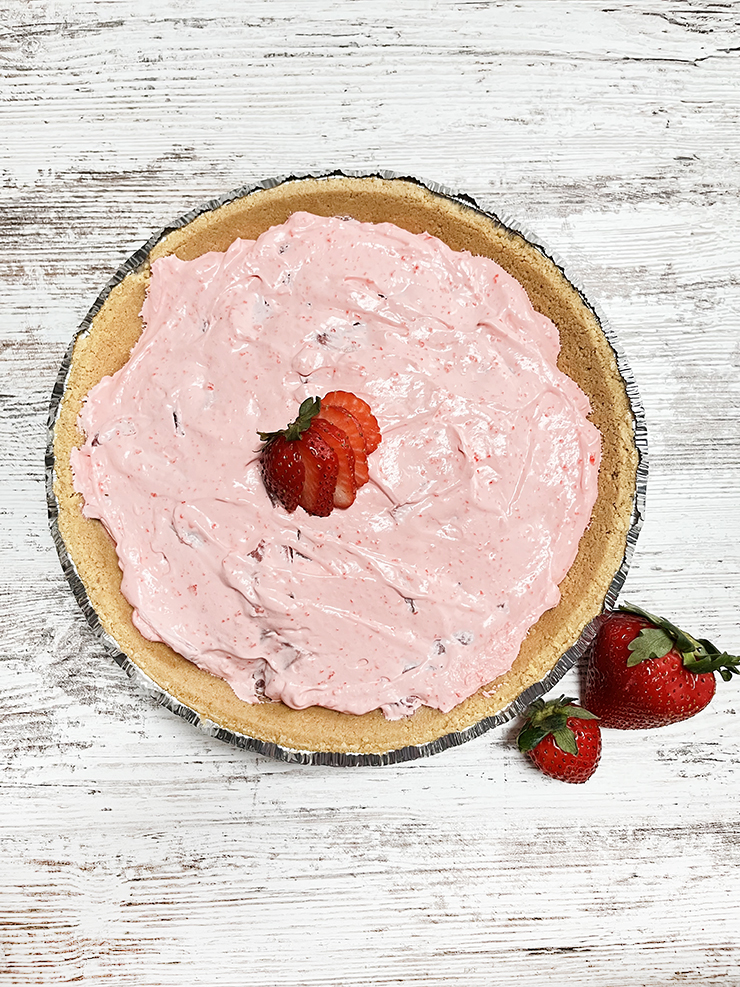 Pink pie on a wooden table with strawberries.