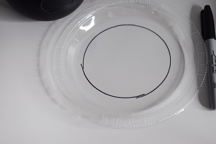 Clear plastic plate with a black circle that was traced around the cauldron.