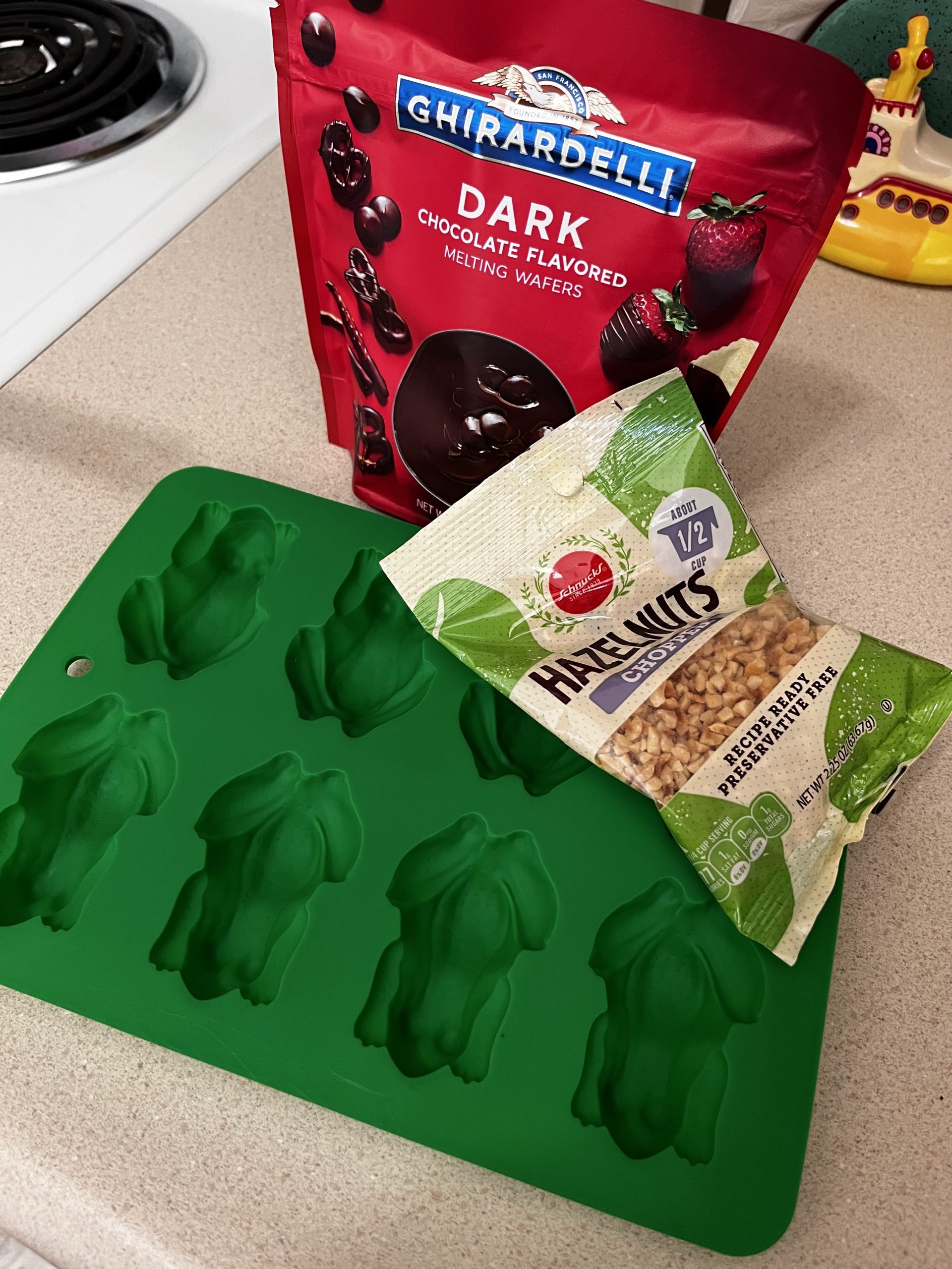 Frog molds, dark chocolate, and a bag of chopped hazelnuts.