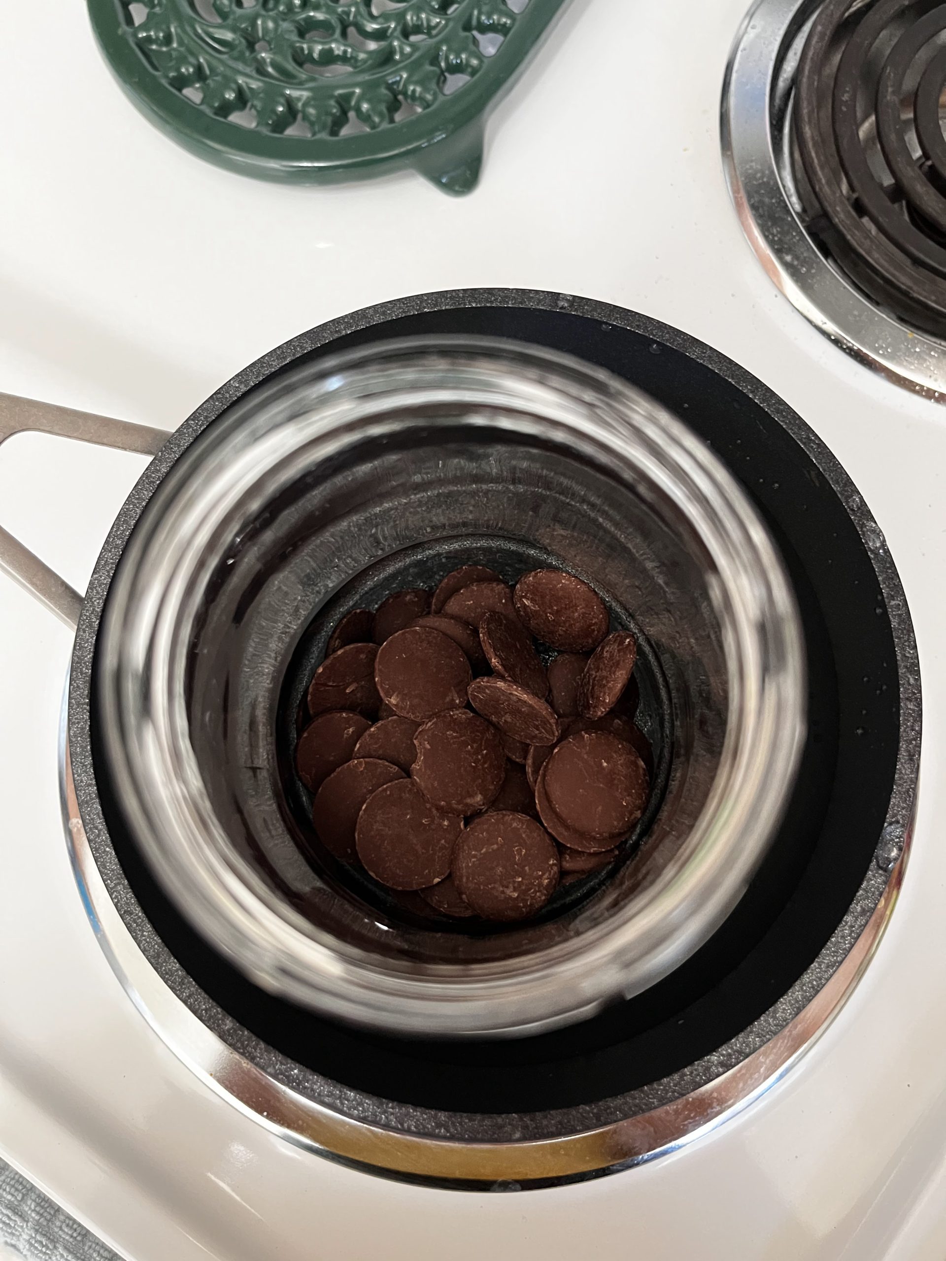 Double boiler on the stove with chocolate that is ready to be melted.