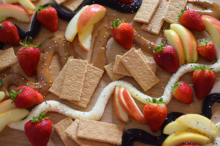 Three-dip dessert board with apples and strawberries.