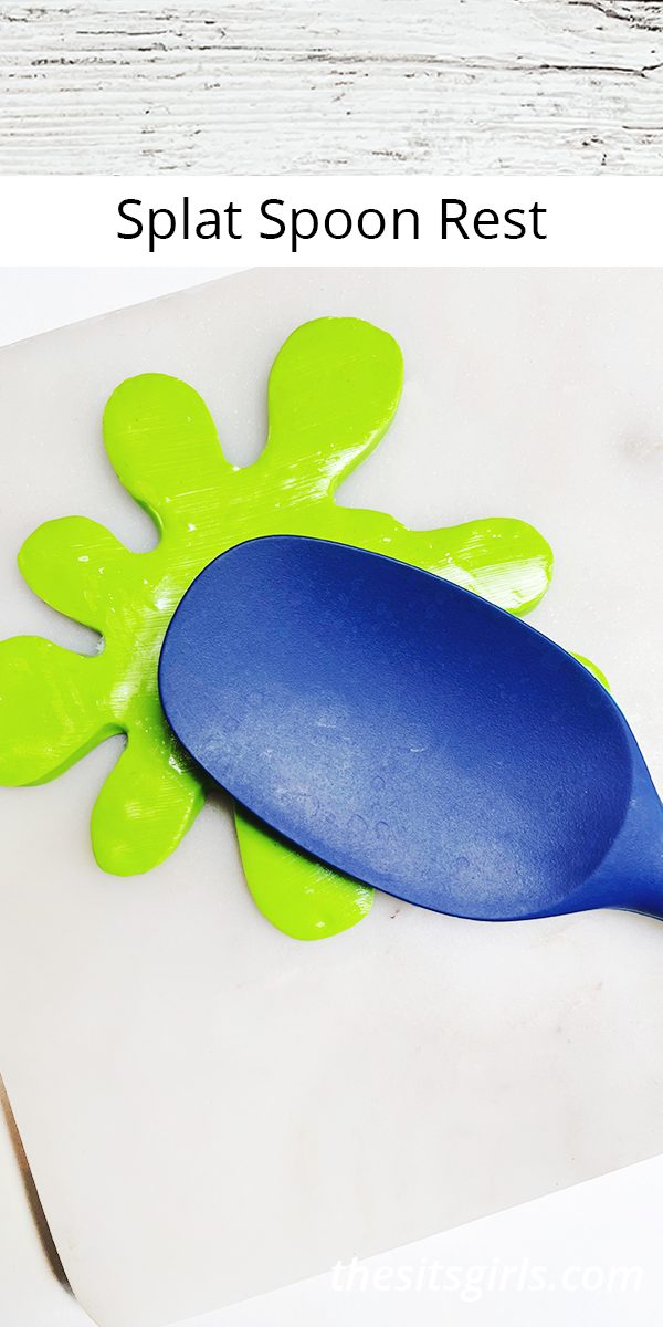 Blue silicone spoon sitting on a bright green spoon rest in a slime splat shape.