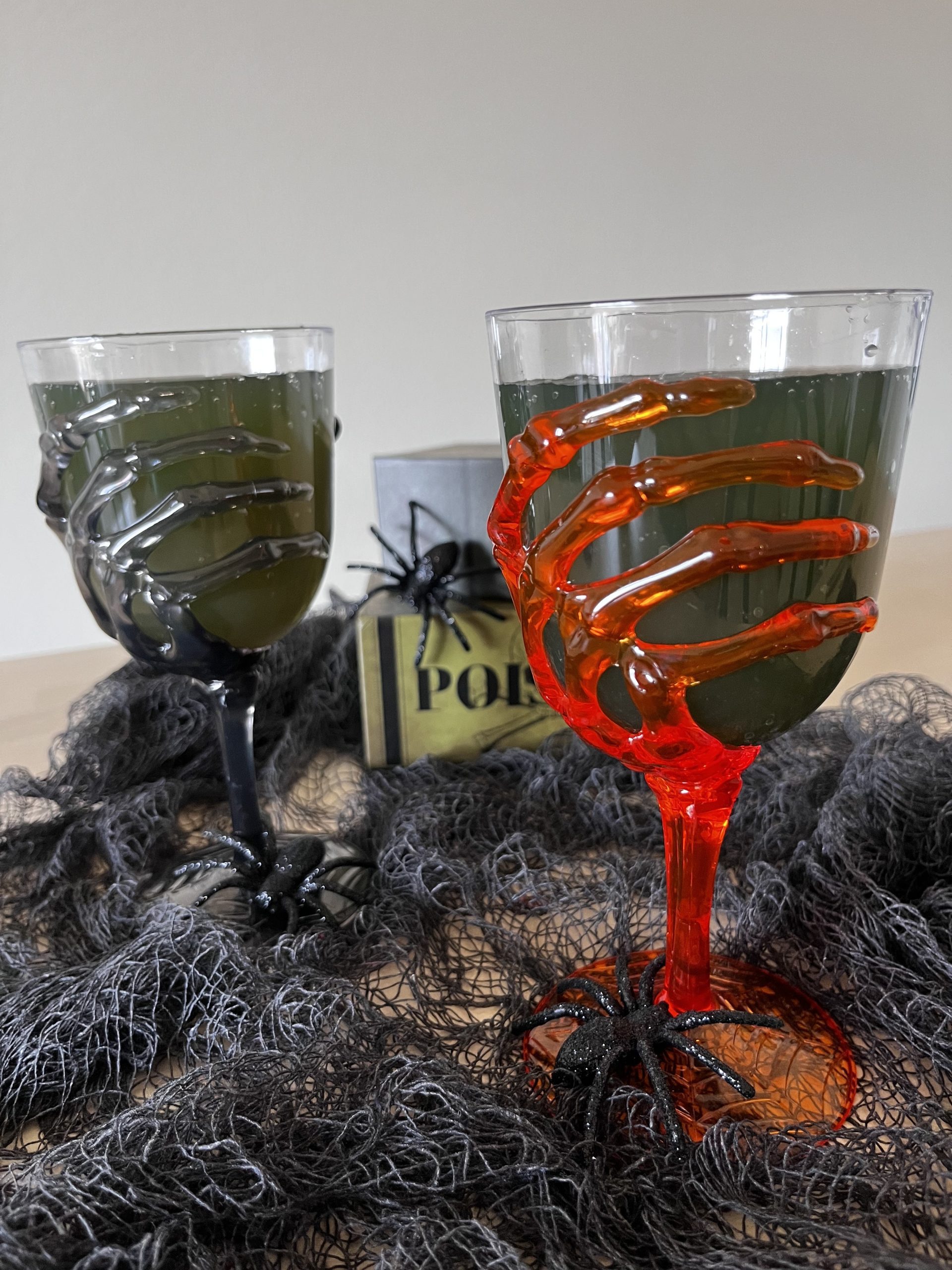 Spooky green drinks in goblets that have skeleton hands. One of the goblets is glowing red.